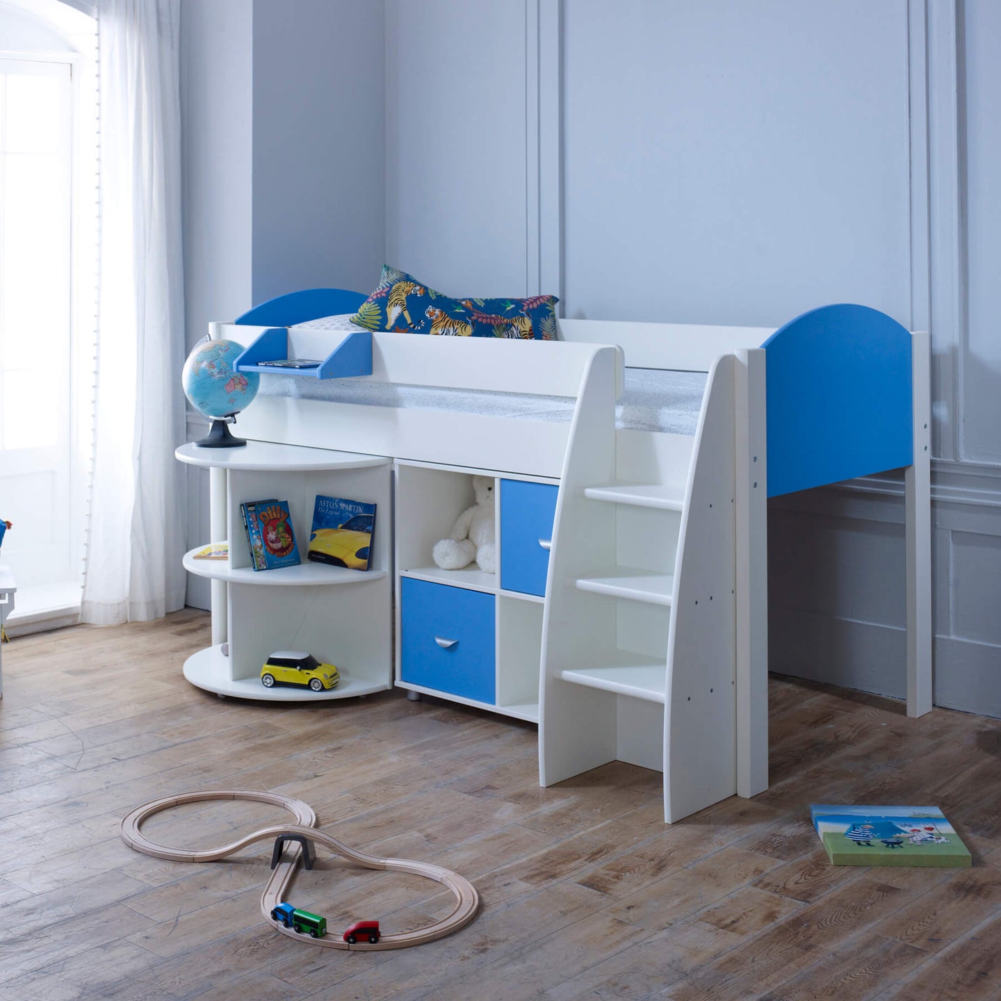 Mid sleeper bed with pull out desk, shelving, and blue storage cubes in a child's room.