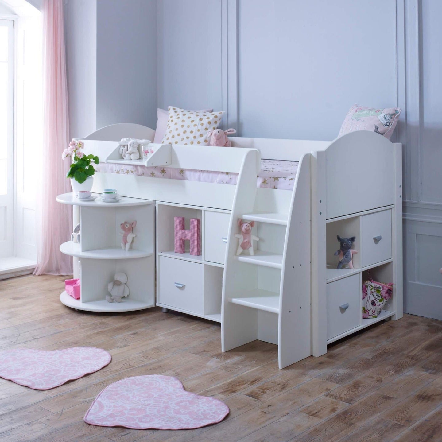 Mid sleeper bed with pull-out desk, storage shelves, and white finish, in a child's room.