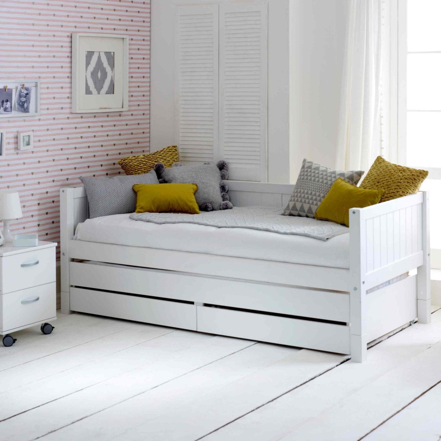 Nordic daybed with trundle pull out and storage drawers in a stylish room.