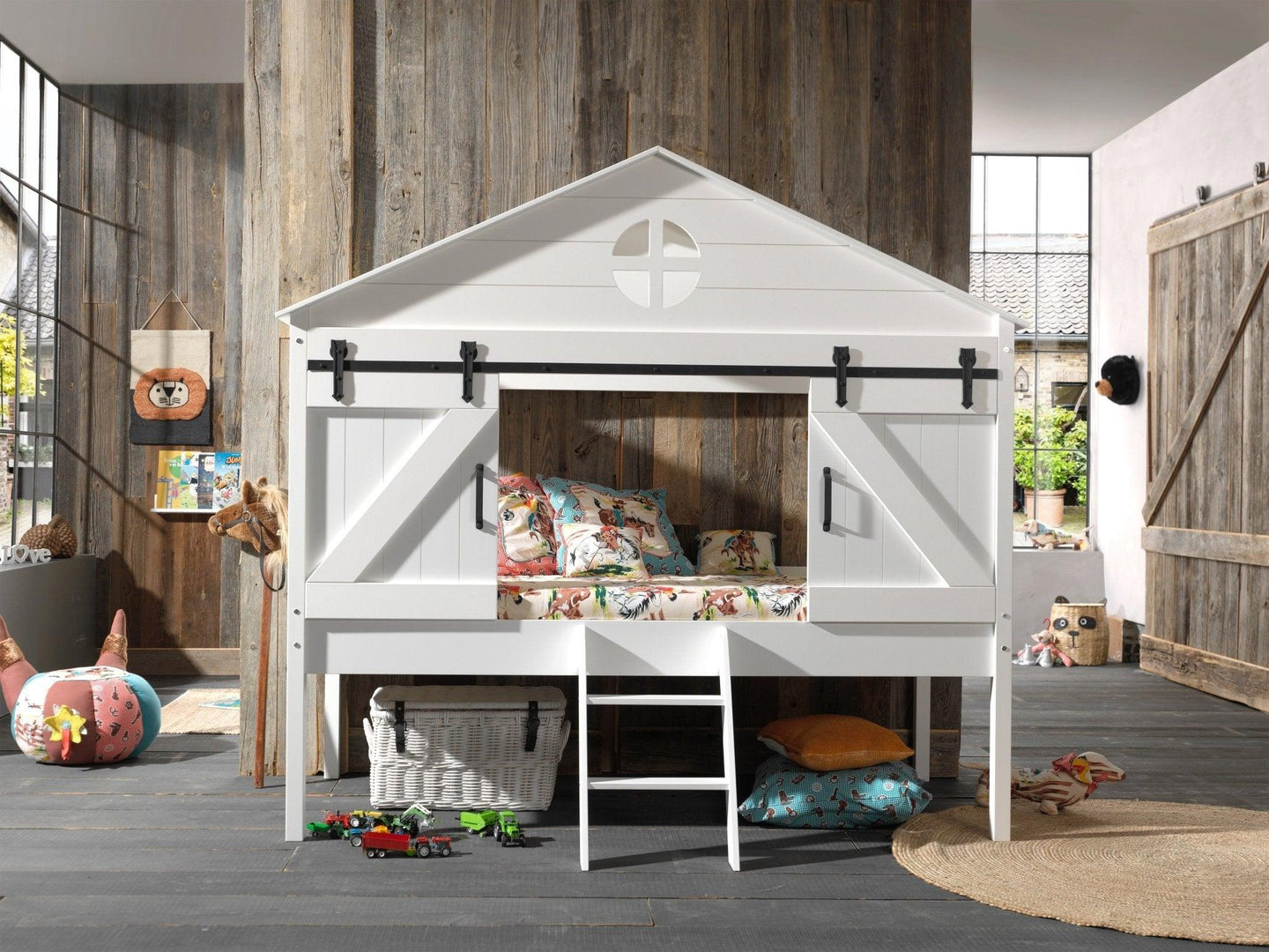 Vipack - Barnie Midsleeper bed with barn-inspired design, white finish, ladder, and sliding doors, in a cozy children's room setting.